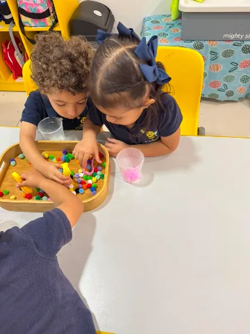 Dos niños de Bee Bright trabajando con material Montessori sobre una mesa del salón