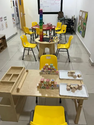 Salón preparado de Bee Bright, con mesas bajas y estantería de materiales Montessori